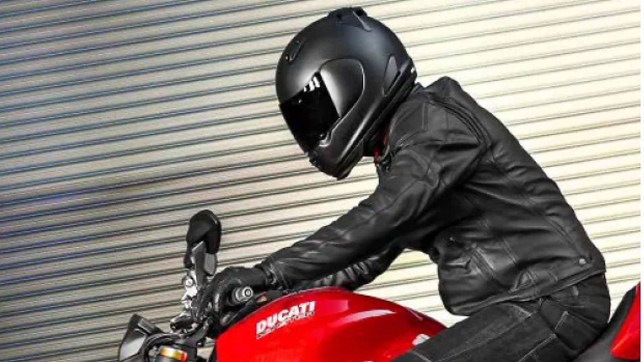 Motorcyclist in a black helmet on red motorbike
