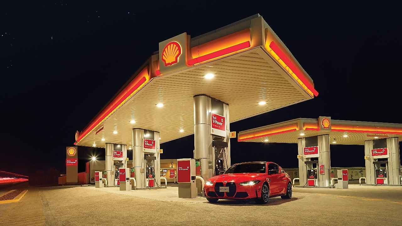 A red BWM M3 parked on a Shell Forecourt during dusk