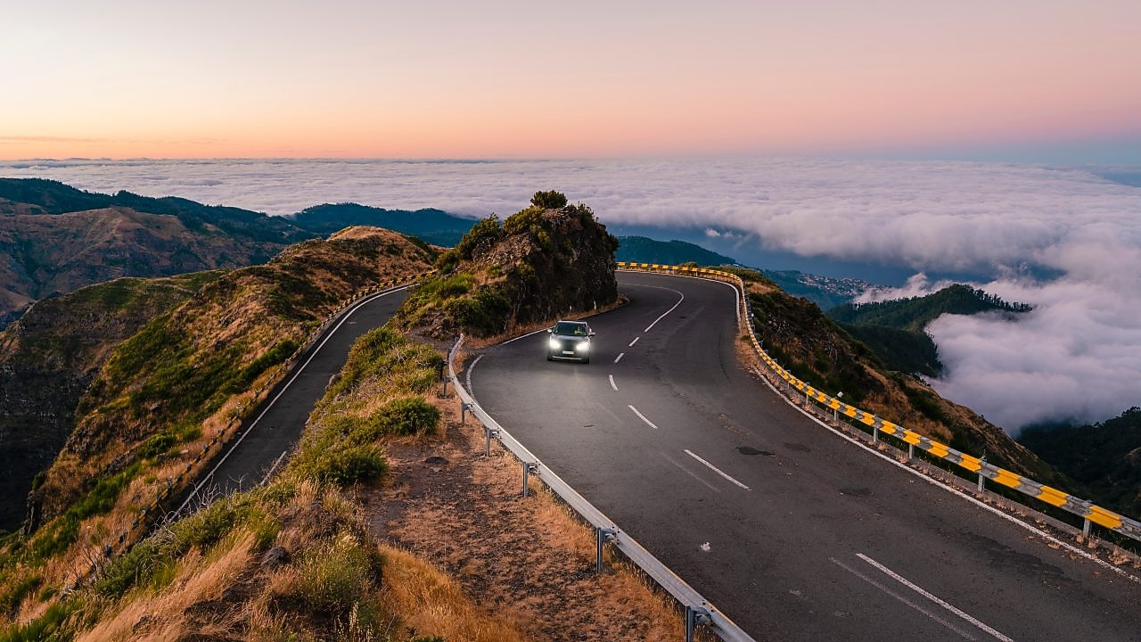 Car driving with headlights on a coastal route