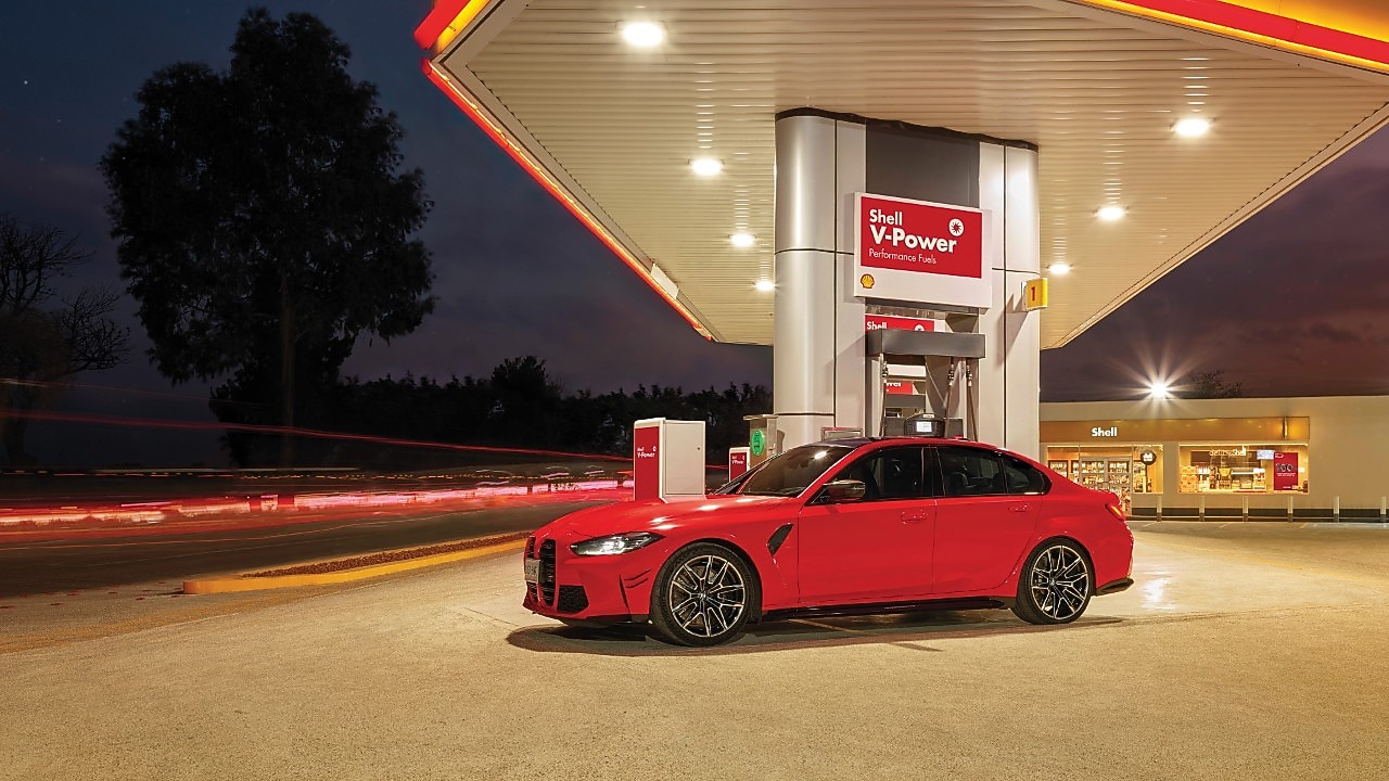 A red BWM M3 parked on a Shell Forecourt during dusk