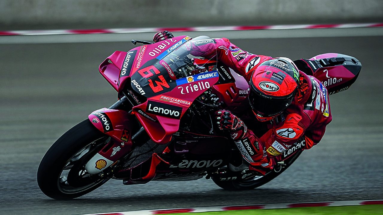 A red Ducati MotoGP bike taking a sharp turn on a race track